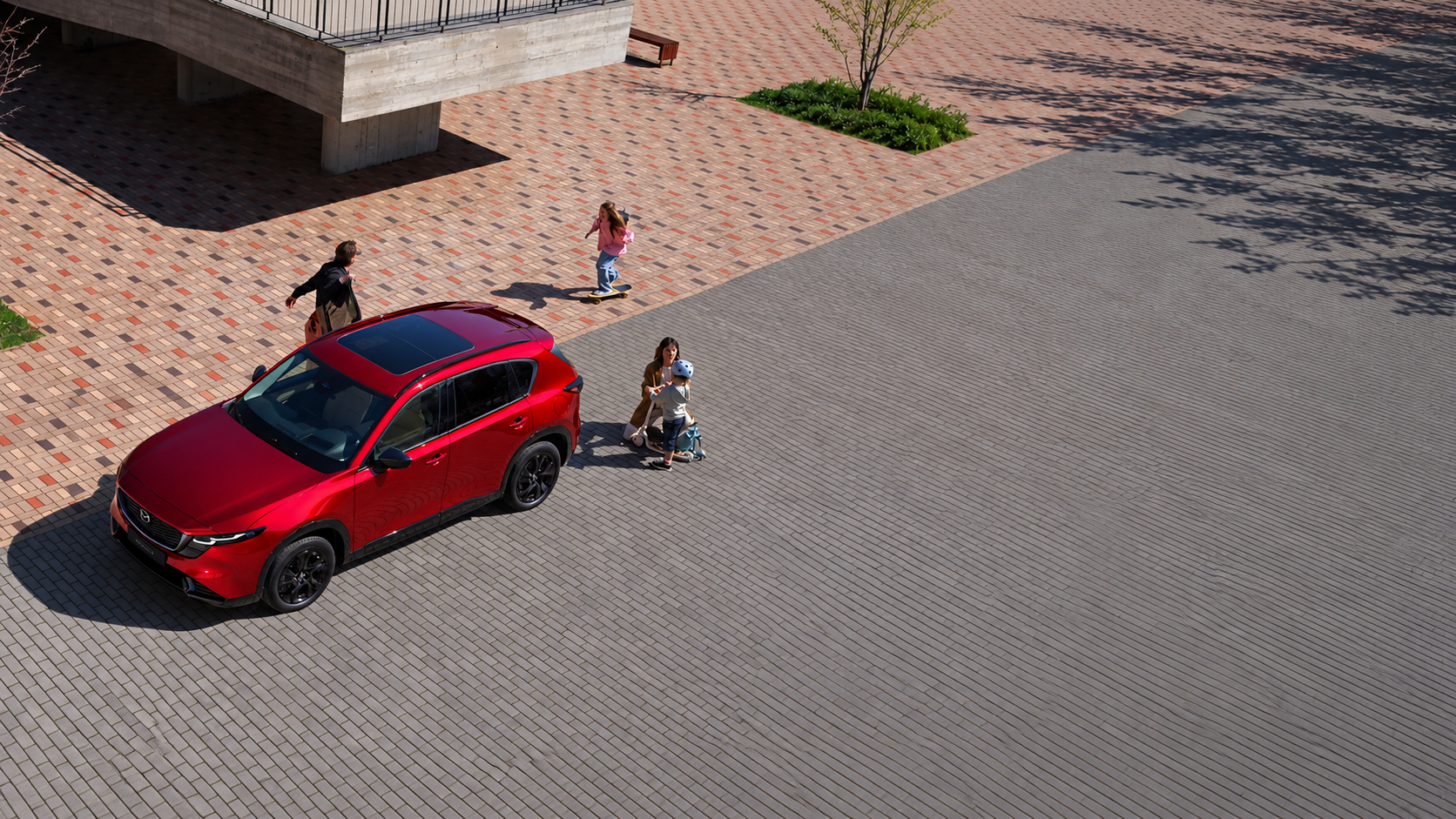 Red Mazda SUV on a paved plaza, viewed from above