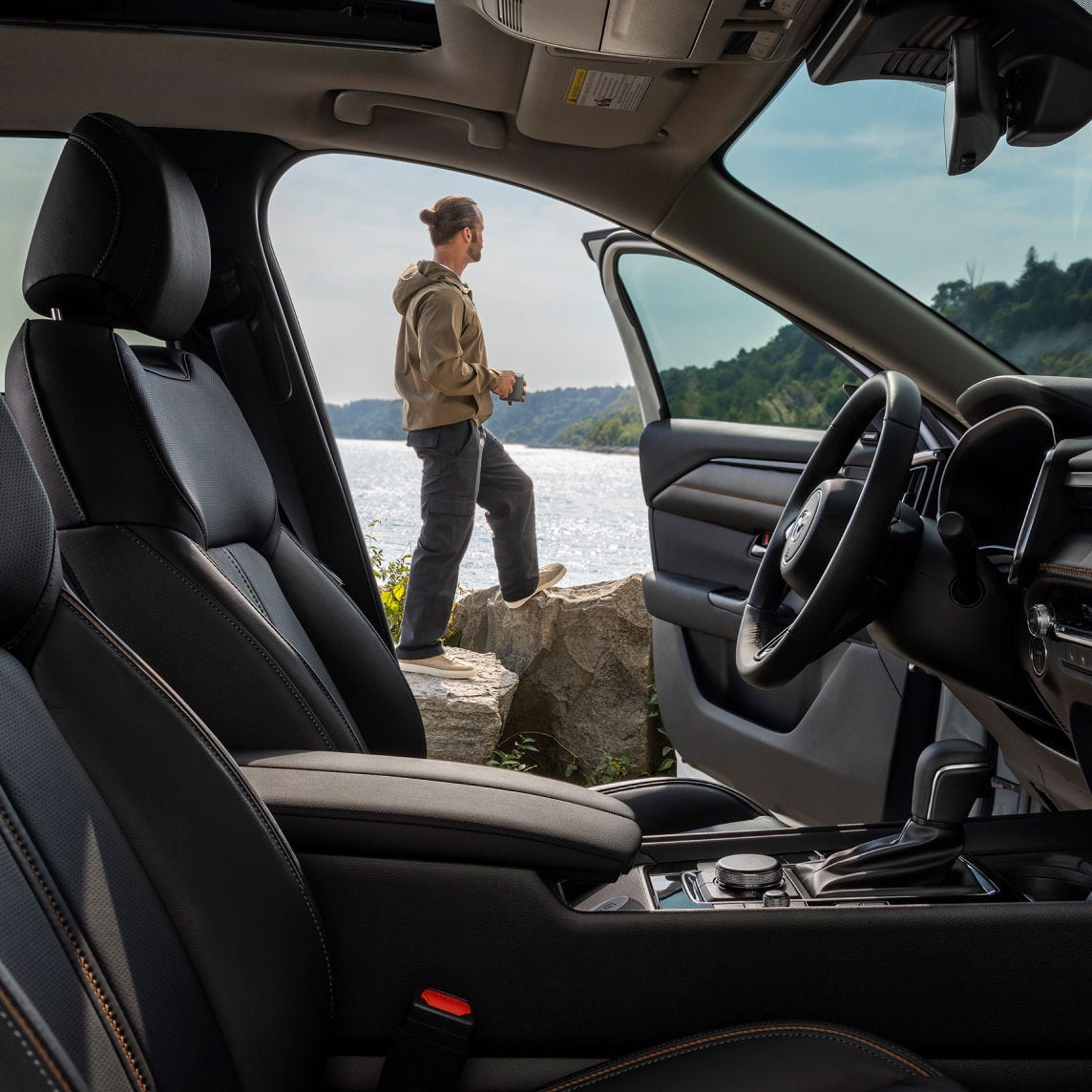 Man standing beside an open Mazda SUV door, viewed from the cabin