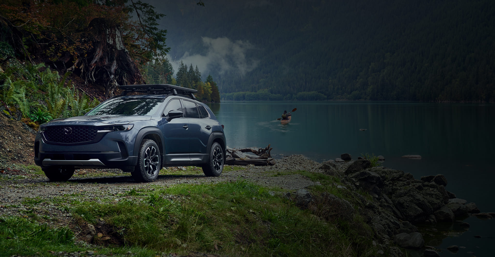 Blue-gray 2026 Mazda CX-50 by a forest lake