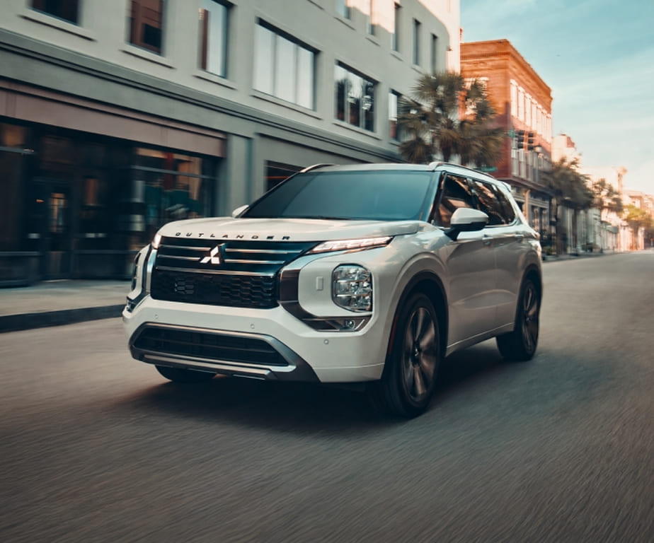 White Mitsubishi Outlander driving through a city street