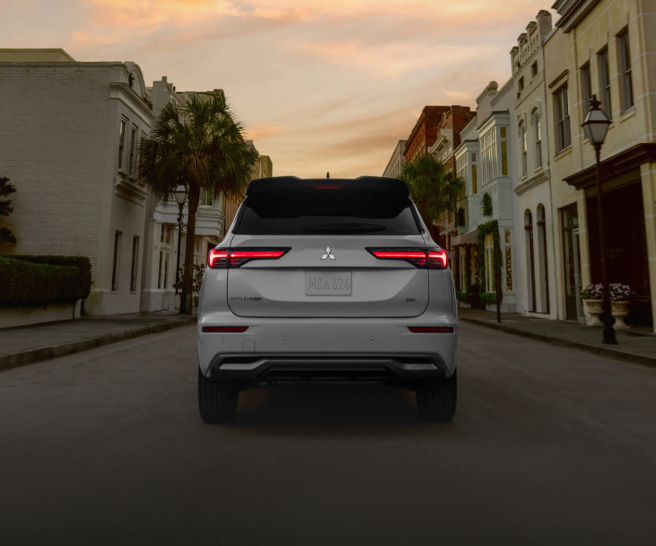 Rear view of a white Mitsubishi Outlander on a city street at dusk