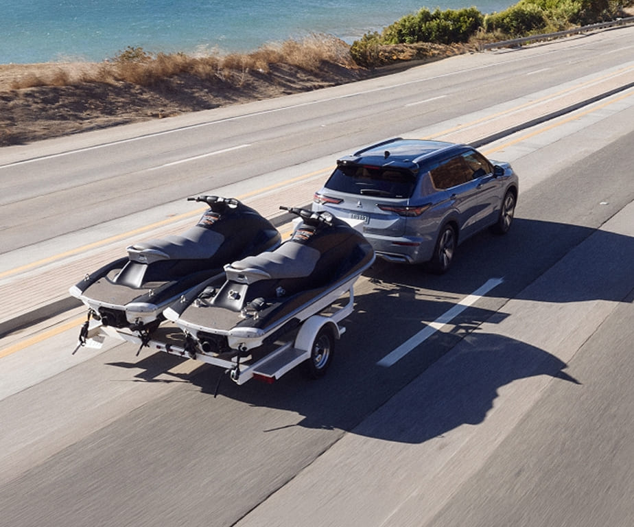 Mitsubishi Outlander towing two personal watercraft on a highway